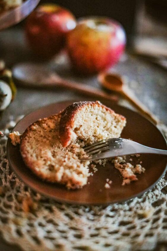 apple cider donut cake, low angle shot of two slices of cake on a wooden plate with a fork