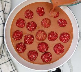 Pouring sauce over meatballs lined in white skillet