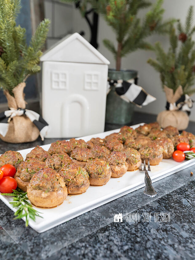 Easy stuffed mushrooms ready to serve on a white platter and garnished with fresh rosemary and grape tomatoes