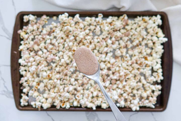 Adding cinnamon spiced melted white chocolate to popcorn