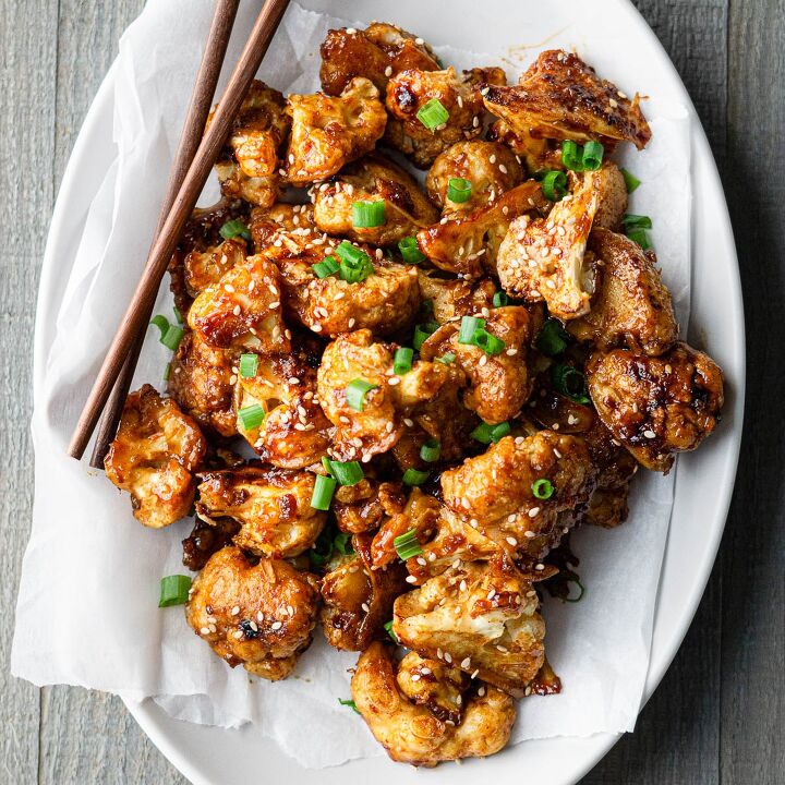 vegan gochujang cauliflower wings, Gochujang Cauliflower wings garnished with sesame seeds and green onions and served with chopsticks