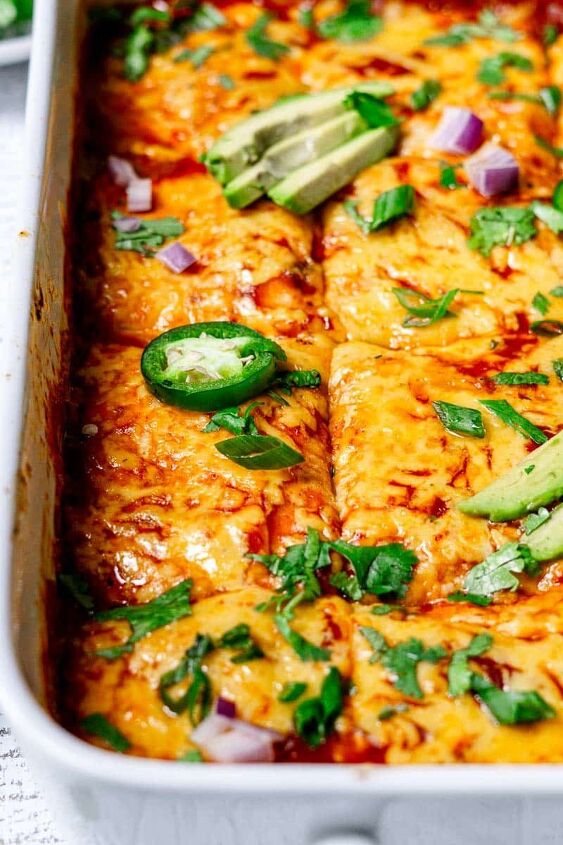 vegetarian enchilada casserole, enchilada casserole served in a casserole dish topped with avocado and jalapenos
