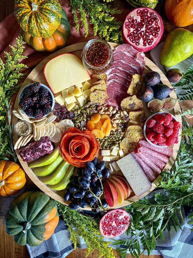 fall charcuterie board happy honey kitchen, A fall charcuterie board arranged with three different types of cheese and variety of fruit and meat are on a round wooden board Greenery and fresh pumpkins surround the board