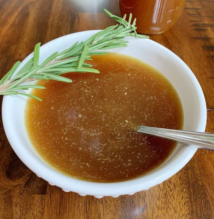 crock pot chicken bone broth, Chicken Bone Broth in a white bowl with a spoon and sprig of rosemary