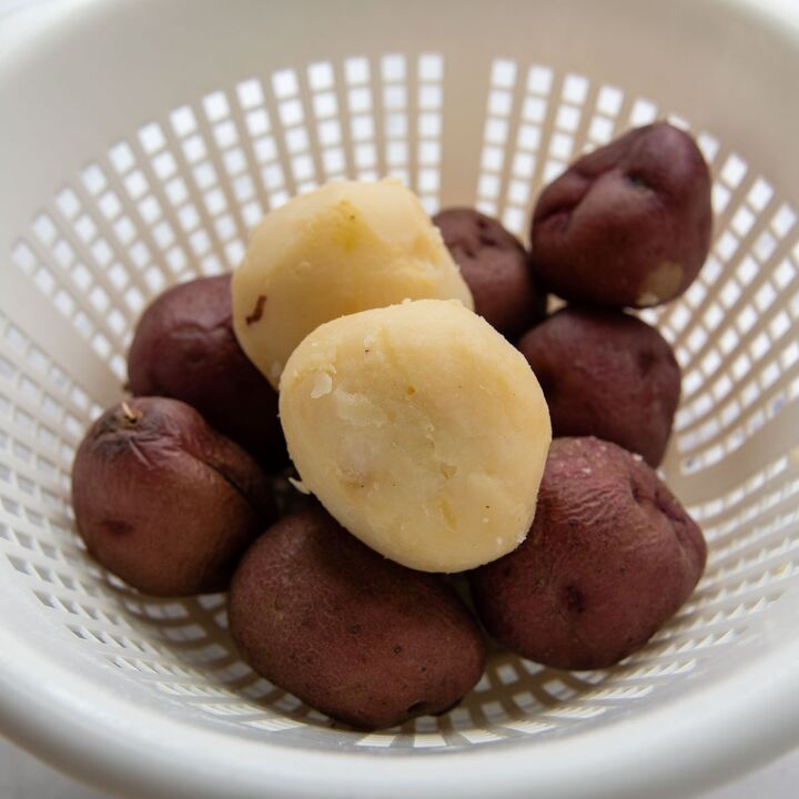 amish potato salad gluten free, boiled potatoes in a colander with one peeled