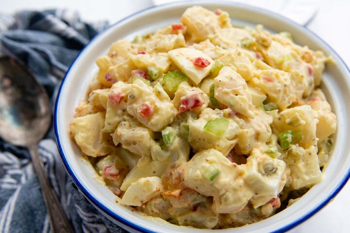 amish potato salad gluten free, a horizontal view of a bowl of potato salad with a blue linen and serving spoon next to it