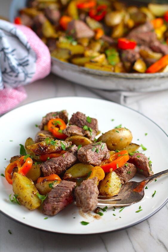 mouthwatering potato and steak bites recipe, Garlic Potato and Steak Bites Recipe with sweet pepper slices on a plate with pan on counter It s an easy and delicious one pan family dinner You get fantastic salty buttery tender steak and potatoes in each and every mouthwatering bite