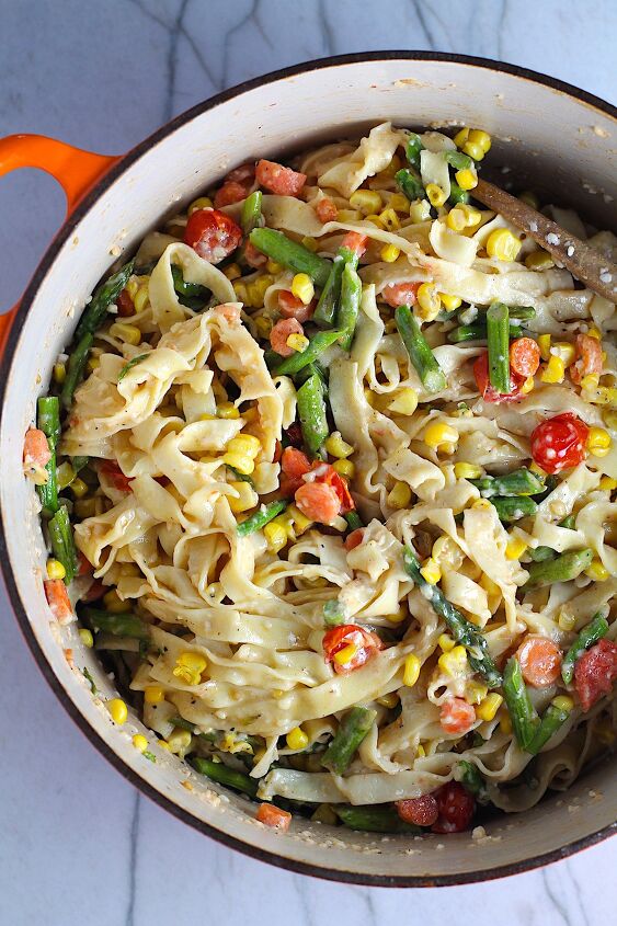 roasted vegetable pasta primavera recipe, Fresh Creamy Pasta Primavera Recipe in a pot on counter with fettuccine parmesan cheese roasted asparagus carrots tomatoes and fresh corn kernels