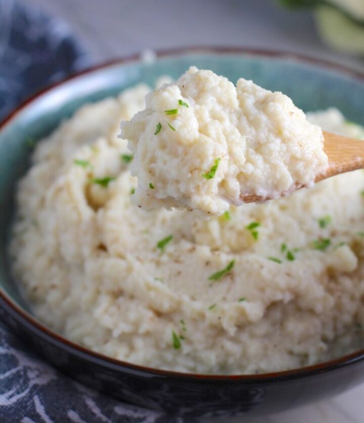 easy mashed roasted cauliflower and garlic, Mashed Roasted Cauliflower in a bowl with spoon scooping The texture is perfectly creamy and along with the flavor mimics mashed potatoes