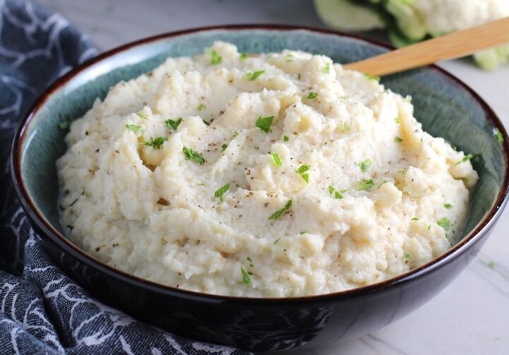 easy mashed roasted cauliflower and garlic, Mashed Roasted Cauliflower in a bowl with spoon The texture is perfectly creamy and along with the flavor mimics mashed potatoes One of the best holiday side dishes