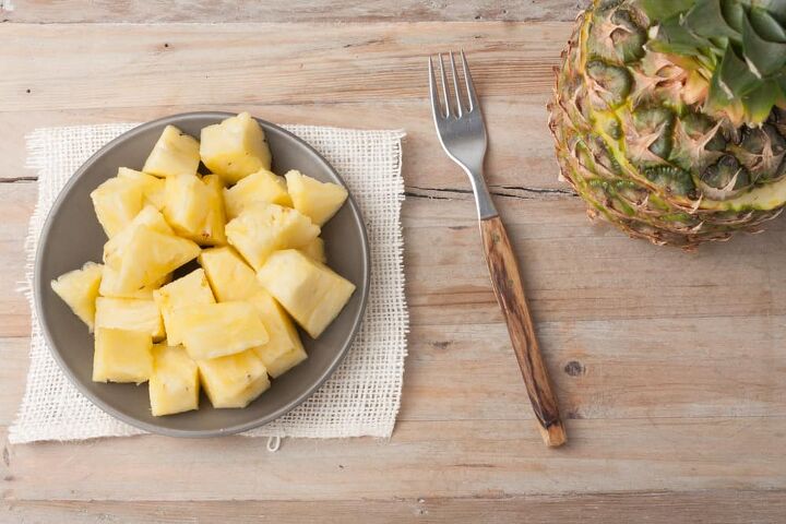 white wine sangria recipe with fresh herbs, pineapple chunks on a plate on wooden rustic background