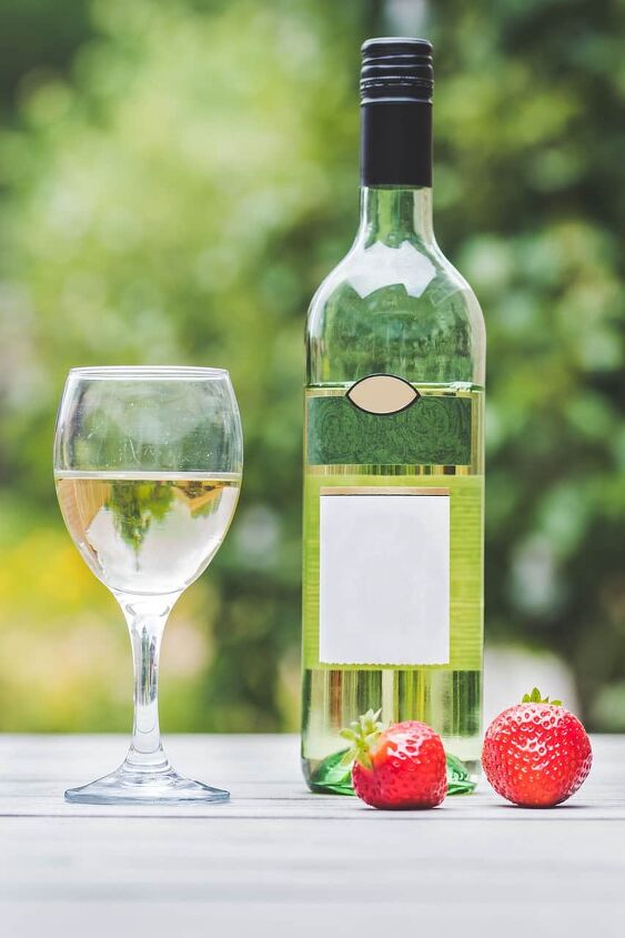 white wine sangria recipe with fresh herbs, bottle of white wine and glass of wine with strawberries on table