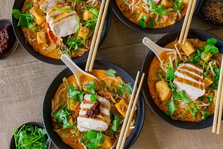 thai chicken laksa, Thai laksa served in a bowl with chicken noodles herbs and toppings