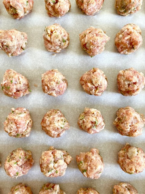 mini meatball italian wedding soup, Uncooked meatballs lined up on parchment paper