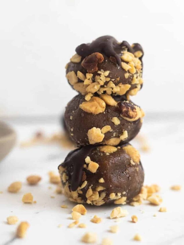 no bake peanut butter bliss balls, Peanut butter bliss ball in a stack with crushed peanuts around it on a marble table