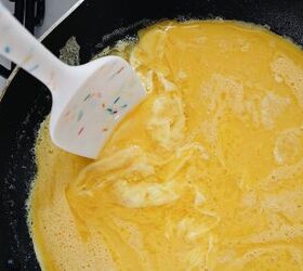 easy breakfast quesadillas, scrambled eggs being cooked in a non stick skillet with butter