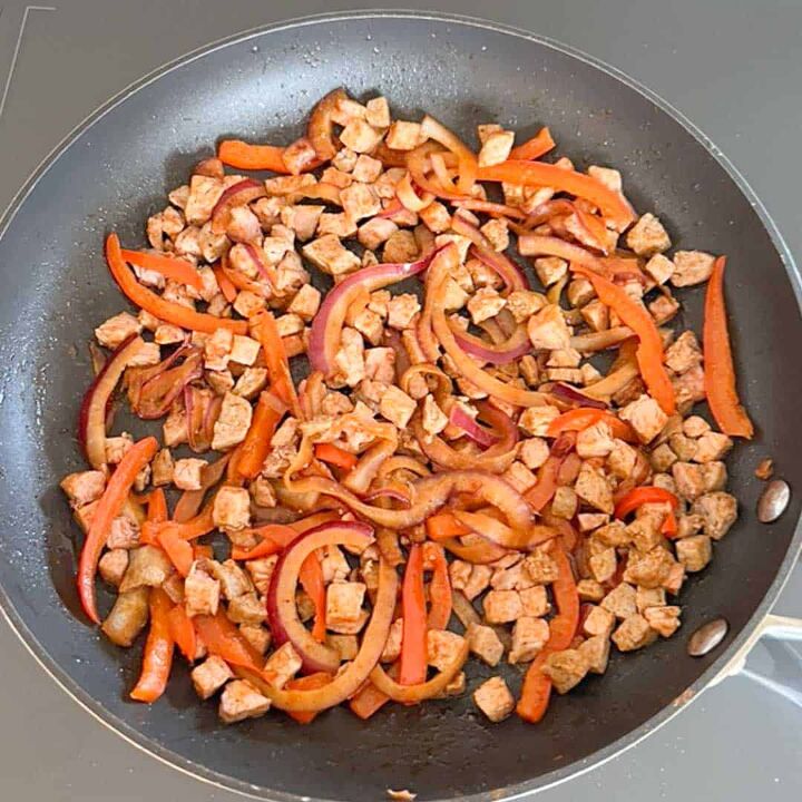 leftover pork tenderloin quesadillas, overhead shot of cooking onions peppers pork and sausage in a skillet