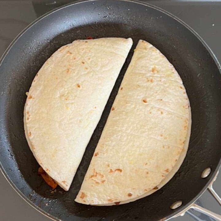 leftover pork tenderloin quesadillas, two stuffed tortillas folded over cooking in a skillet side by side