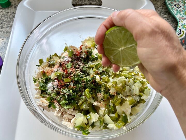 ultimate chicken casserole recipe coxinha chicken bake, Hand squeezing lime over a bow filled with shredded chicken cream cheese cilantro onions green pepper and seasonings for the Ultimate Chicken Casserole Recipe