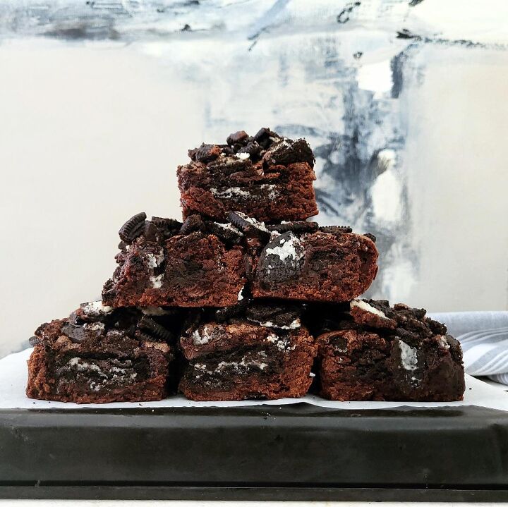 oreo brownies, oreo brownies cut into squares and stacked in the shape of a pyramid three on the bottom two in the middle and one on top background is abstract gray black and white canvas painting