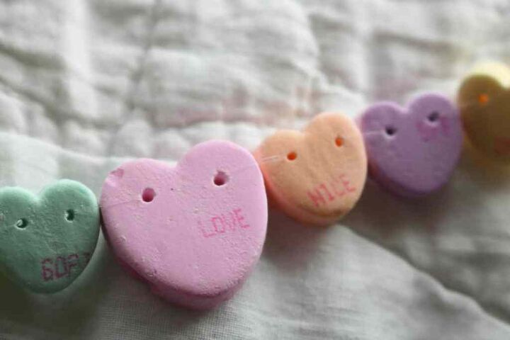 how to make a candy heart necklace, closeup of nylon string on conversation heart craft