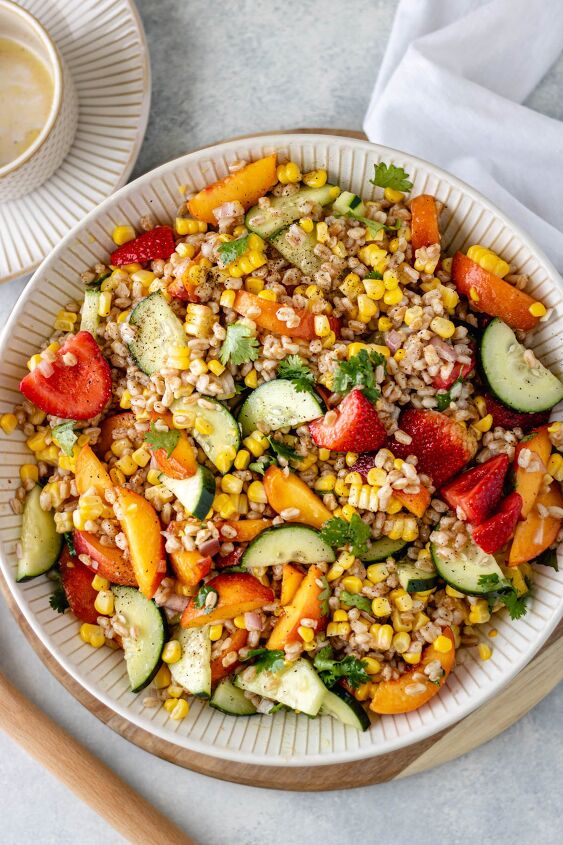peach cilantro farro salad, A large serving bowl filled with a Peach Cilantro Farro Salad and drizzled with a homemade vinaigrette and salt and pepper