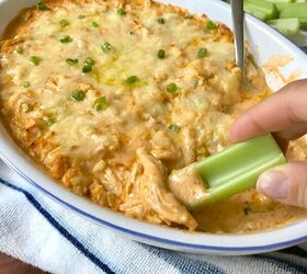 buffalo chicken dip with greek yogurt, Hand with celery scooping Buffalo Chicken Dip with greek yogurt in serving dish with spoon in it