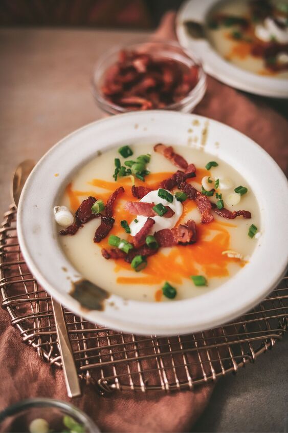 easy potato soup recipe, A bowl of potato soup with napkin trivet and garnishes