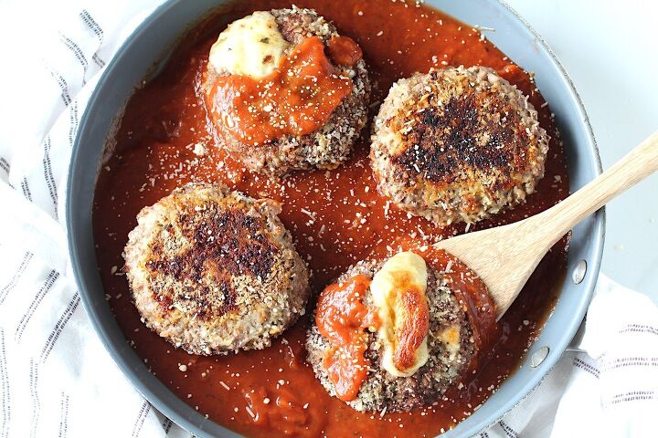 polpettone cheese stuffed meatballs, Four Ground beef Polpettone sitting in tomato sauce in a skillet with mozzarella cheese oozing out of a couple of them