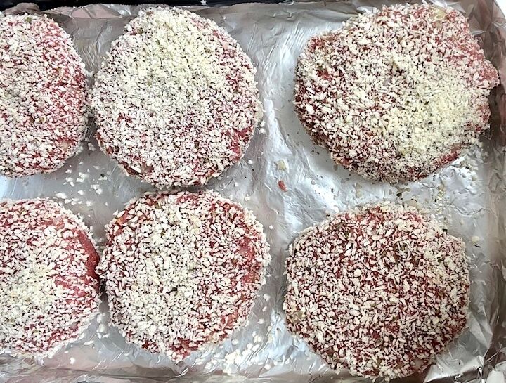 polpettone cheese stuffed meatballs, Six polpettone beef patties that have been coated in breadcrumbs laying on an aluminum lined sheet pan before cooking