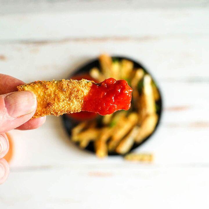 air fryer zucchini fries, Zucchini fry with marinara sauce held up close