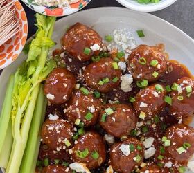 crockpot buffalo bbq chicken meatballs, A round white plate with bbq buffalo meatball appetizers There s topped with blue cheese crumbles and chopped scallions There s 3 small bowls in the background one with toothpicks one with scallions and one with blue cheese There s a couple of stalks of celery on the plate with the meatballs
