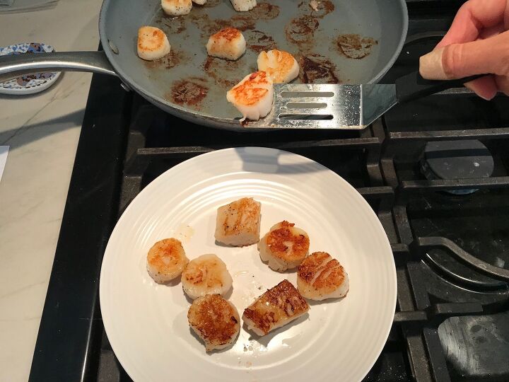 quick glazed pan seared scallops with garlic, Seared scallops being transferred by spatula from pan to plate for Glazed Pan Seared Scallops with Garlic and Honey