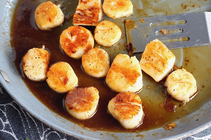 quick glazed pan seared scallops with garlic, Glazed Pan Seared Scallops with Garlic and Honey in a pan with spatula