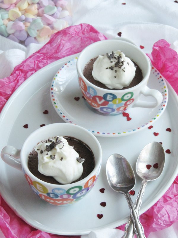 chocolate ganache mousse, two white cups with colorful hearts sitting on a white tray filled with dark chocolate mouse and topped with whipped cream