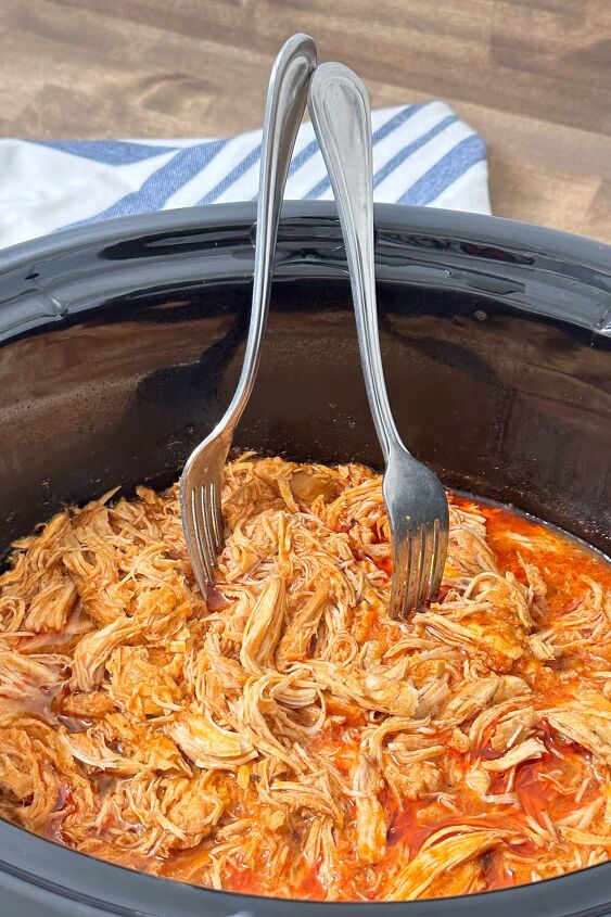 slow cooker buffalo chicken sliders, Shredding the chicken in the crockpot with two forks