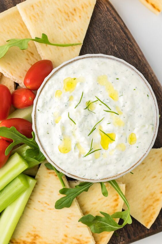 easy tzatziki sauce with sour cream, Tzatziki sauce on a cutting board with celery tomatoes and pita bread