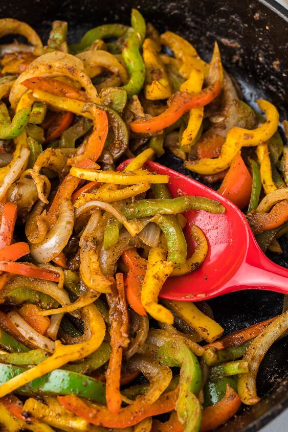 how to saute onions and peppers, Fajita style onion and peppers with a red spoon in a black skillet