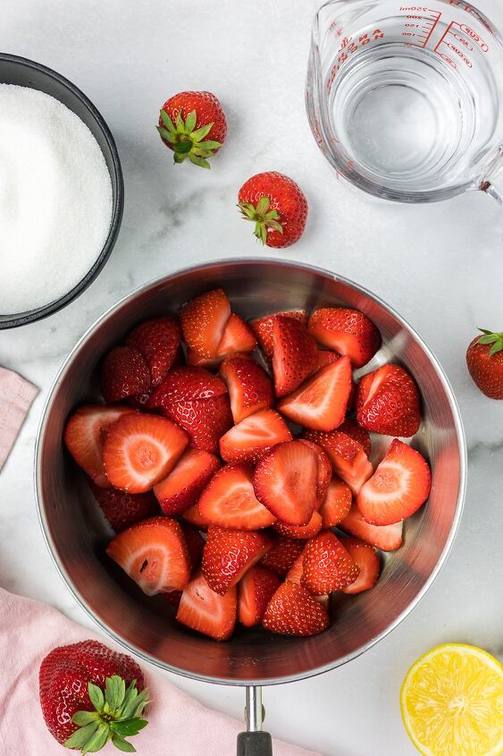 strawberry simple syrup, Sliced strawberries in a sauce pan with sugar and water on the side