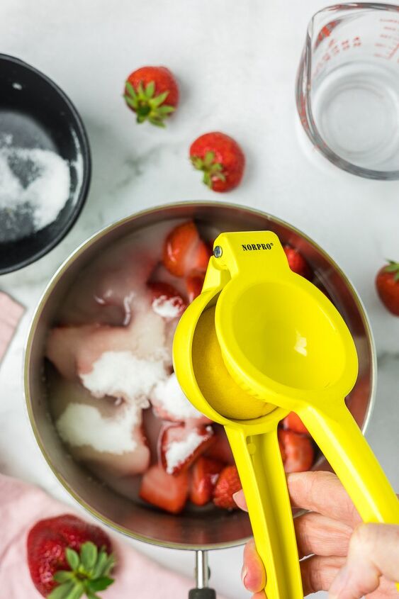 strawberry simple syrup, Lemon juice being squeezed into strawberries sugar and water in a sauce pan