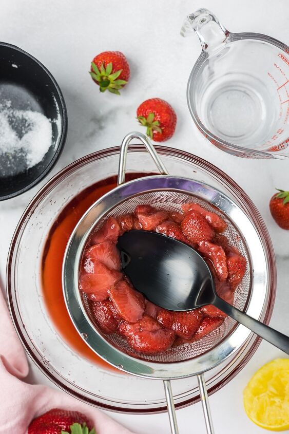 strawberry simple syrup, Strawberries in a strainer with a spoon to get all of the juice from the strawberries