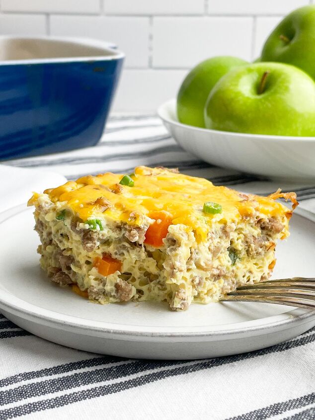 easy cheesy sausage egg bake, piece of sausage egg bake on a white plate with casserole dish and green apples in background