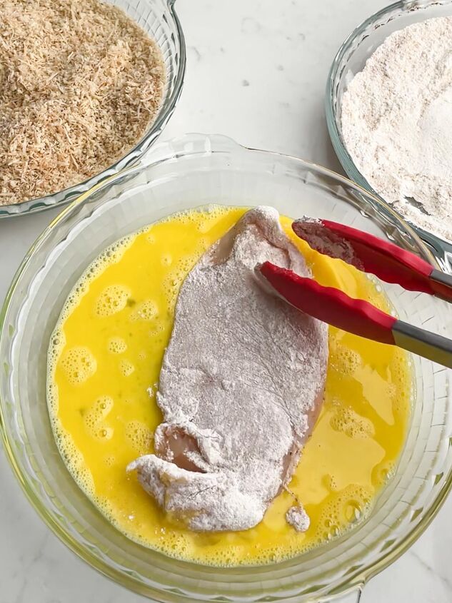 crispy baked thin chicken breasts, tongs dipping flour coated chicken in egg