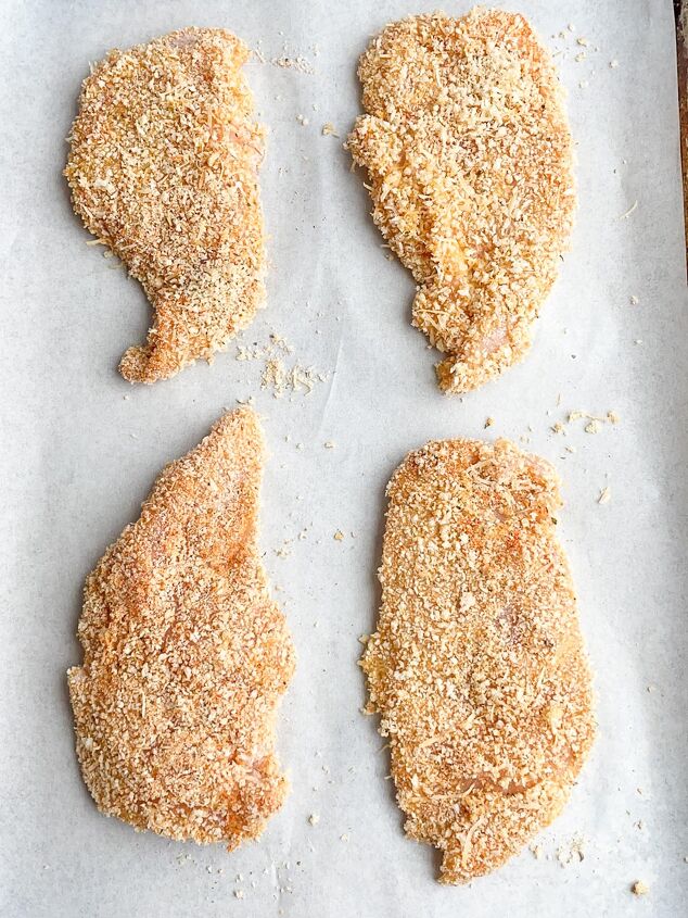 crispy baked thin chicken breasts, panko thin sliced chicken on parchment lined baking sheet