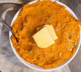the perfect mashed butternut squash sweet potato, butternut squash sweet potato mash in a bowl with butter on top as well as chives and salt and pepper on a wood surface with a tan napkin