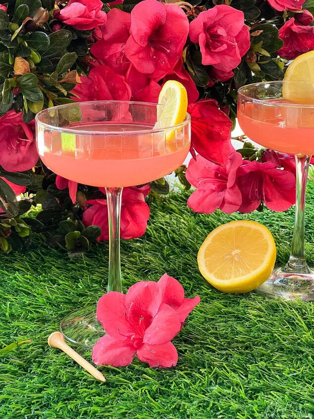 the masters azalea cocktail, Pink Azalea cocktails in coupe glasses garnished with lemon sitting on grass with golf tees and azaleas