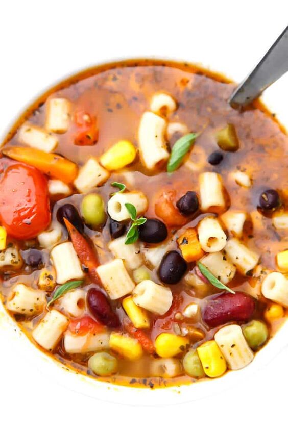 vegan minestrone soup, A top view of a bowl of vegetarian minestrone soup with tomatoes pasta veggies and beans