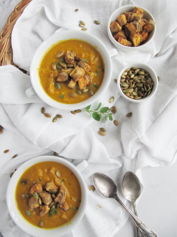 sweet potato and pumpkin soup, Sweet Potato and Pumpkin Soup in two white bowls with handles and a small bowl of pumpkin seeds and roasted sweet potatoes on the side