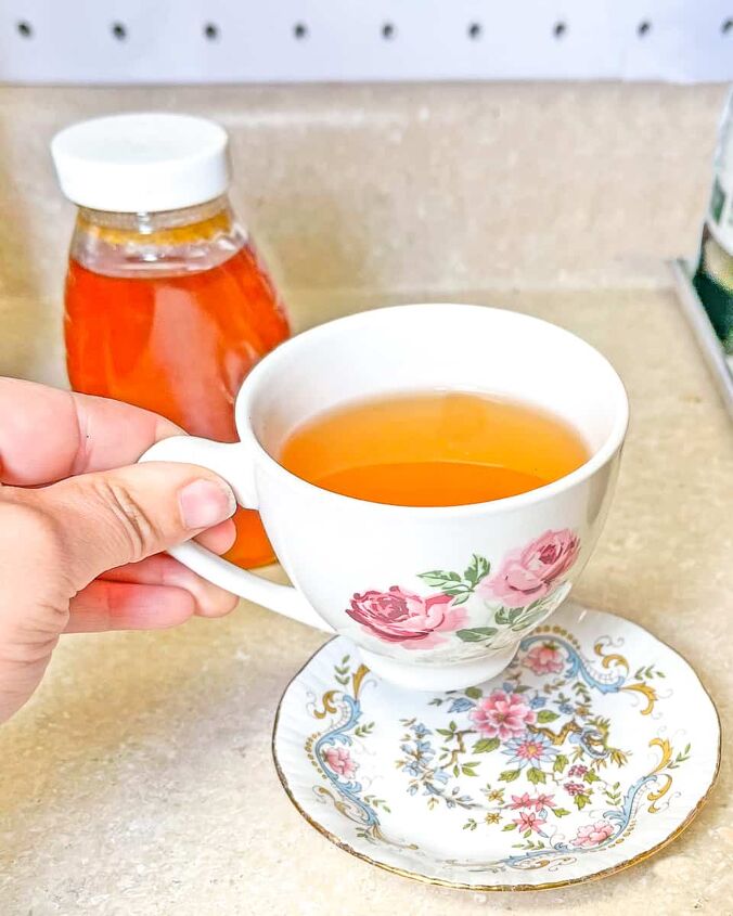 lemon and honey tea recipe, person pickup up tea cup with lemon and honey tea A bottle of honey in the background