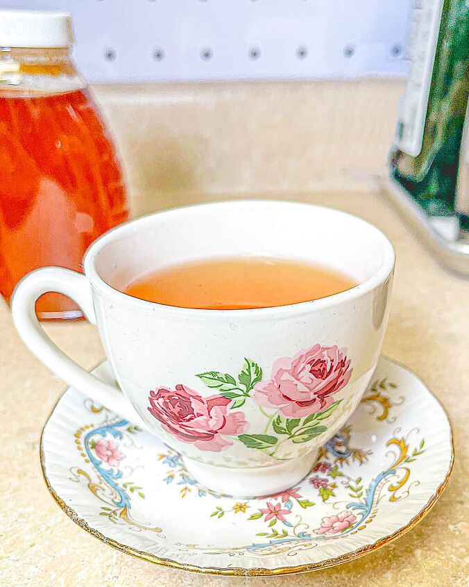 lemon and honey tea recipe, white tea cup with pink roses with lemon and honey tea A bottle of honey in the background